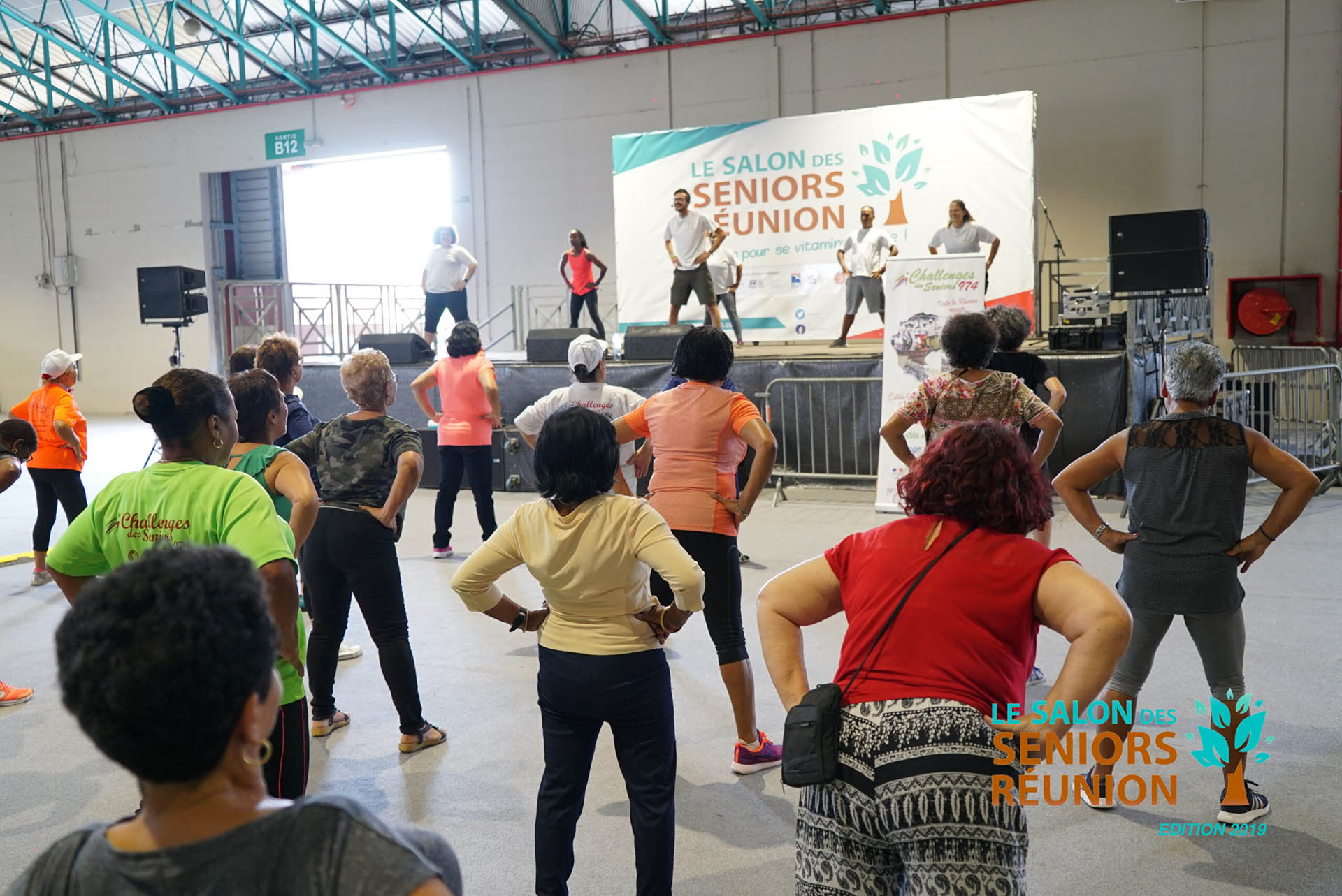 Woman performing a yoga pose on a rocky beach with ocean view and clear blue sky.